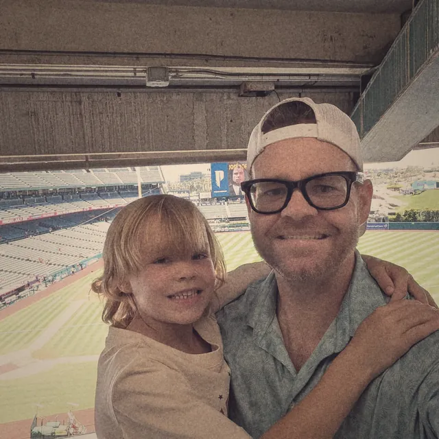 TJ and his son smiling in the upper deck of a baseball stadium