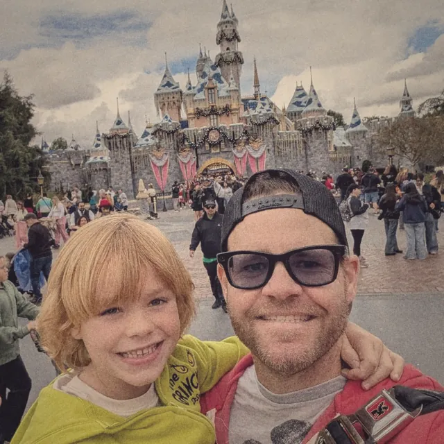 Selfie of TJ and his son in front of the castle at Disneyland