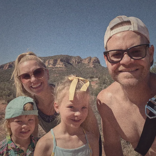 Family selfie on a hike with red rock cliffs behind them